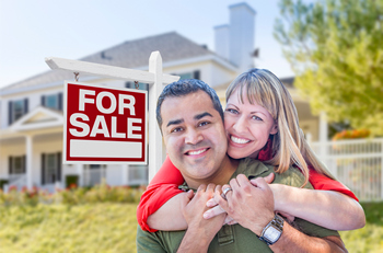 Happy couple standing in front of their new home