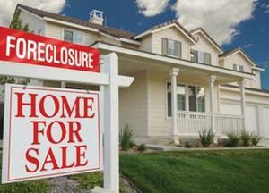 House with a for sale sign and a sign rider that says foreclosure