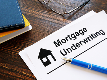 A blue pen and glasses on top of a form with the words mortgage underwriting along the top of the paper.