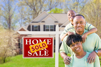 Happy family standinding next to a for sale singn, in front of their new home