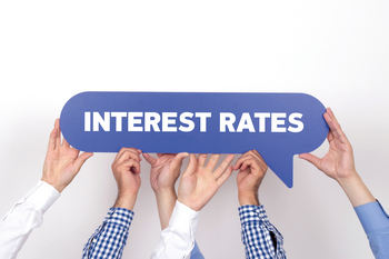 Three people holding up a sign that says interest rates  