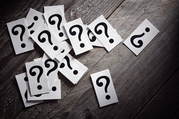 Many paper question mark on a wooden floor
