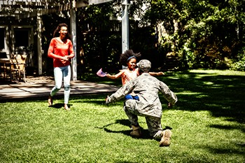 Daughter welcoming her military father in the backyard